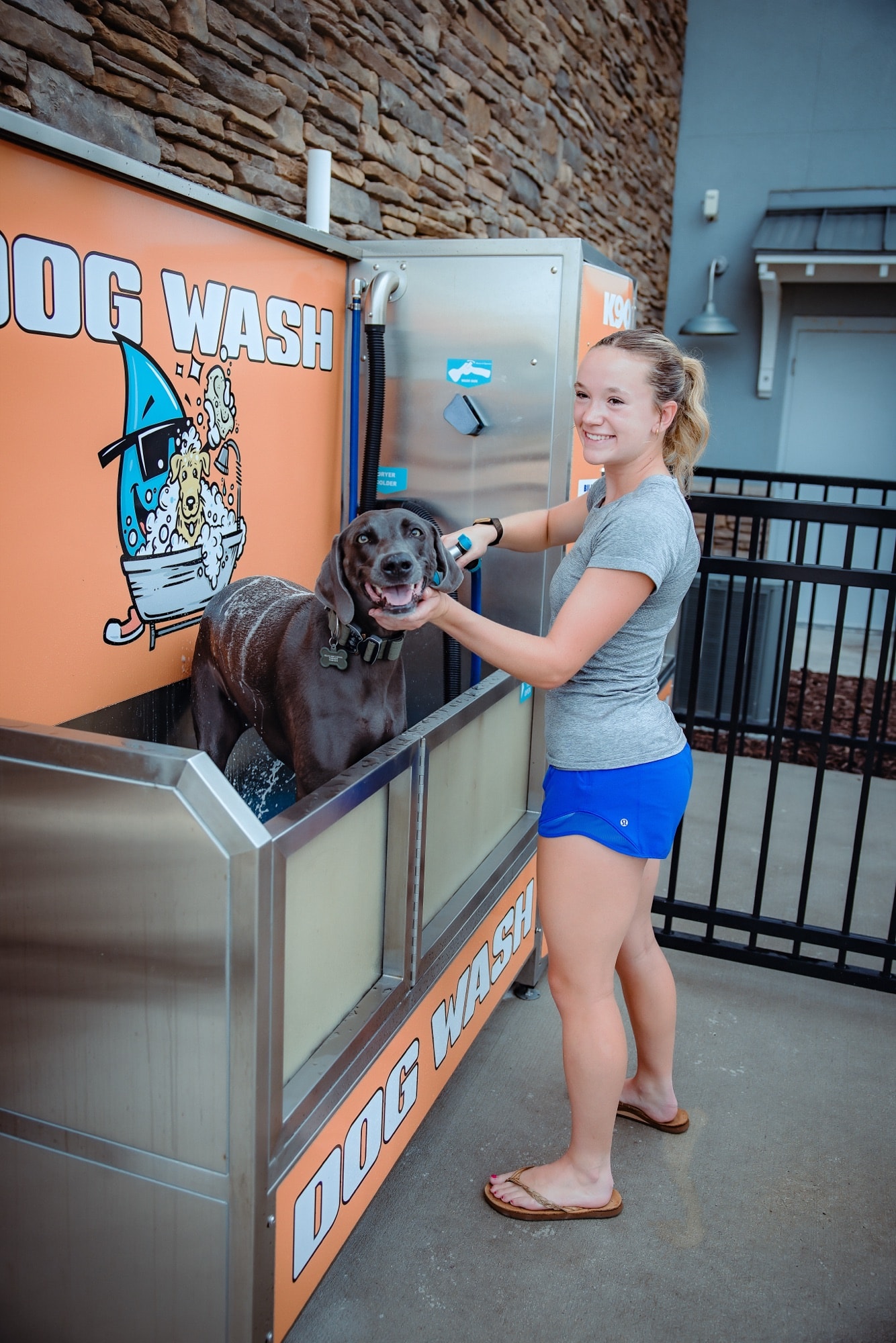 A customer rinsing her dog at the self-serve dog wash
